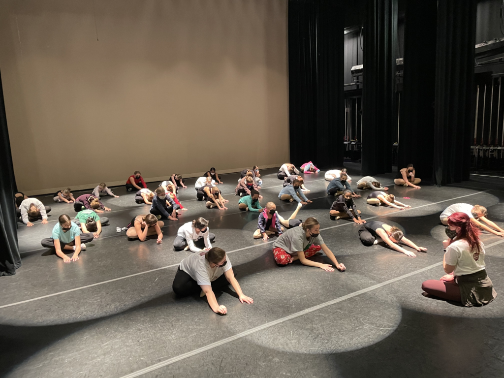 Dance students stretching on stage before performance