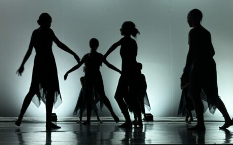 Dancers in silhouette on stage during a performance. 